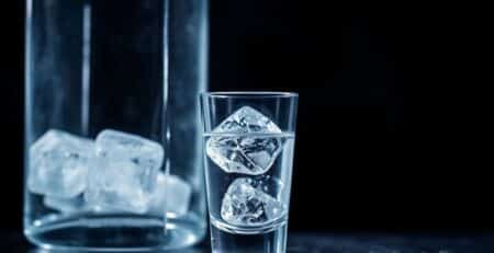 Bouteille de vodka avec un verre et des glaçons.